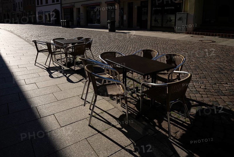 Tables and chairs of a restaurant or bar, empty, backlit, cobblestones, Luther city Wittenberg, Saxony-Anhalt, Germany