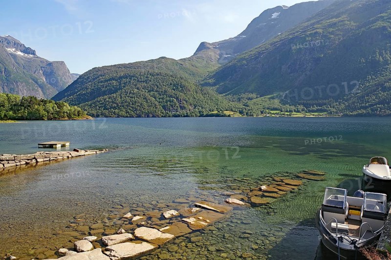 A boat is moored on a jetty in a clear mountain lake, surrounded by green mountains, Eikesdalsvatnet, Aursjövegen, More og Romsdal, Norway