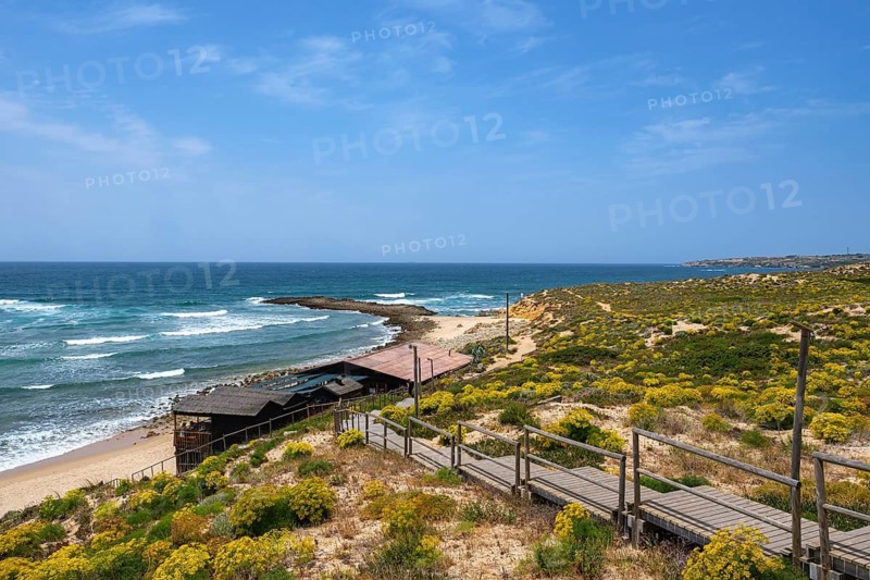 Coastal view of a secluded beach with cliffs and a wooden promenade, Vila Nova de Milfontes, Beja, Portugal
