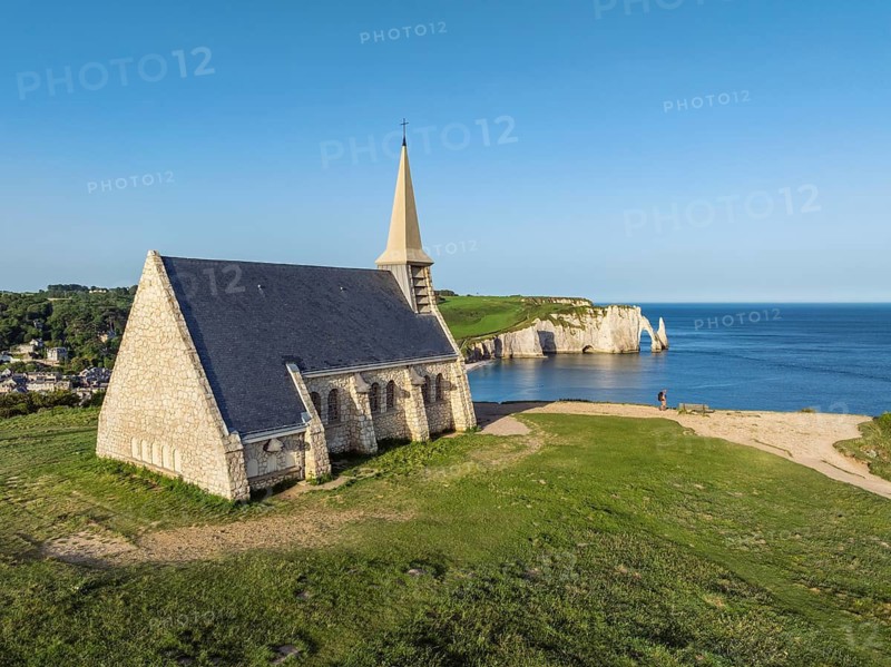 Aerial view of the Notre Dame de la Garde chapel after sunrise at the Falaise d'Amont viewpoint, on the horizon the Porte d'Aval rock formation, Étretat, Alabaster Coast, La Côte d'Albâtre, chalk cliffs, English Channel, Seine-Maritime, Normandy, France