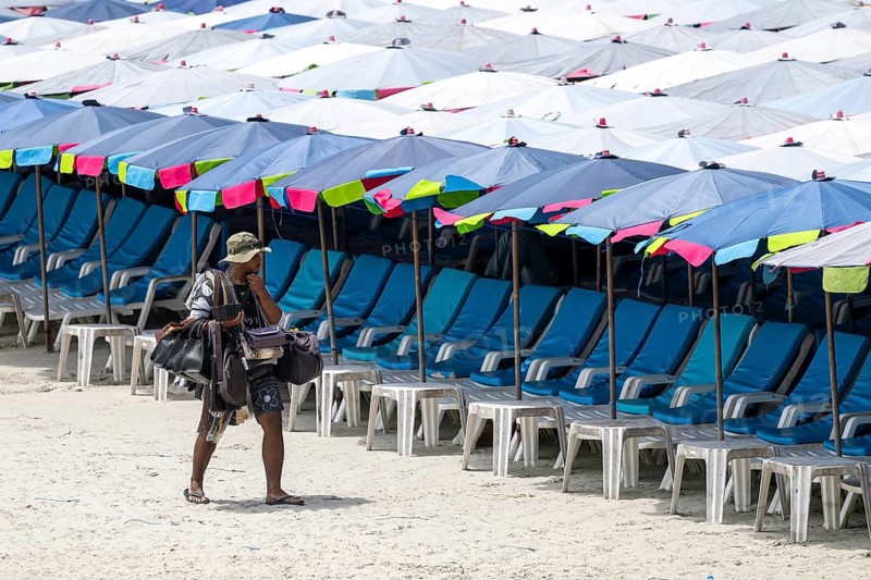 Beach vendor in front of empty sun loungers, Koh Larn, Thailand