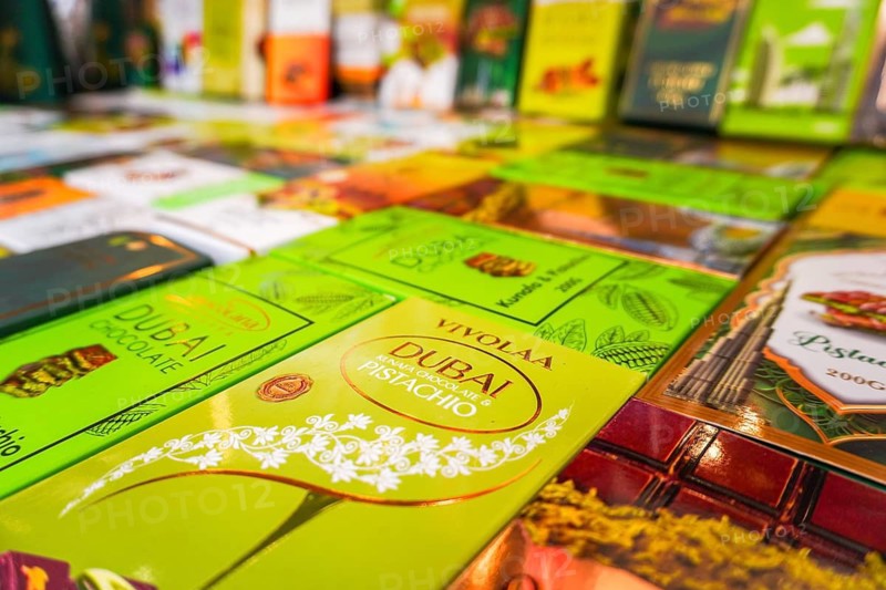 Dubai, UAE - 16th january, 2026: Selective focus colorful Dubai chocolate bars shelf. Pistachio, kunafa, milk chocolate flavors in bright green, yellow, orange packaging. Middle Eastern souvenir market display