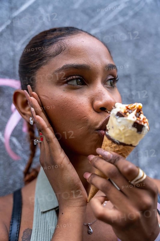 Young woman eating a sweet ice cream cone, experiencing pleasure and refreshment on a hot day, with a close up portrait showing her enjoying the dessert