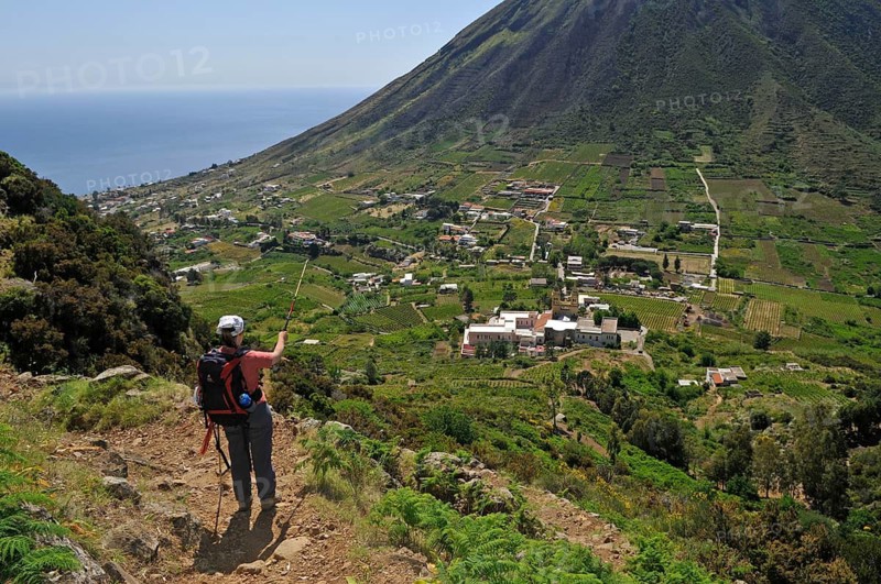 Woman with backpack looking towards Leni and Rinella, Salina, Aeolian or Aeolian Islands, Sicily, Southern Italy, Italy