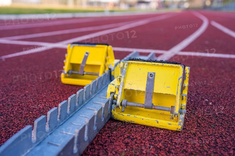 Two yellow starting blocks on a red track, ready for the next challenge