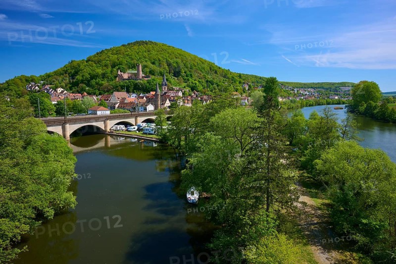 River landscape with bridge and castle on a wooded hill surrounded by a picturesque town and lush greenery, Franconian Saale, Main, Gemünden am Main, Main-Spessart district, Spessart, Mainfranken, Lower Franconia, Bavaria, Germany
