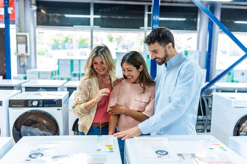 Happy family exploring washing machines and other household electronics, smiling and discussing options in an appliance department or home improvement store