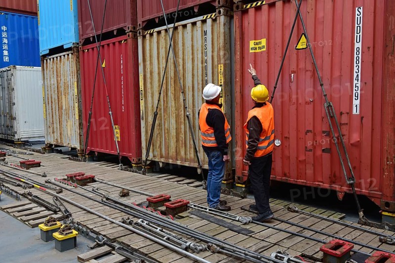 Two workers in safety equipment discuss in front of stacks of containers in the port, workers at the tie rods on a container ship, Schleswig-Holstein, Germany