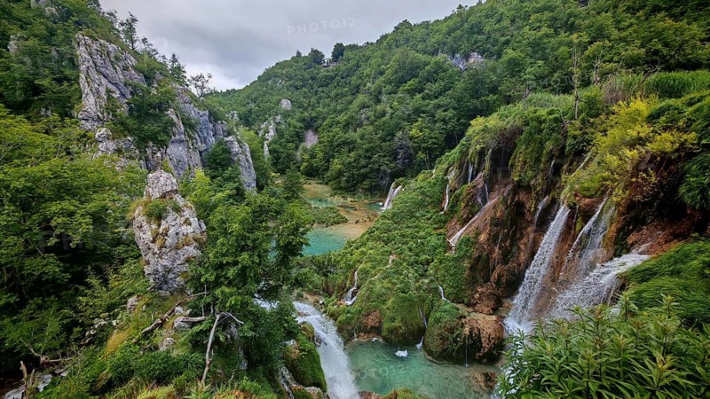 Spectacular waterfalls falling into a river nestled in green mountain scenery, Plitvice Lakes National Park, Croatia