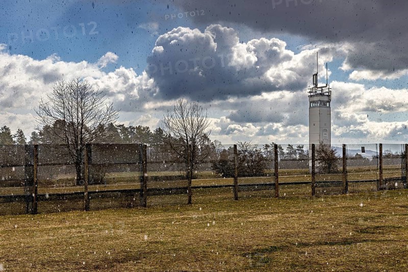 A meadow with a watchtower and a fence in the rain under dramatic cloudy skies, The Point Alpha memorial between Rasdorf and Geisa in the Rhön