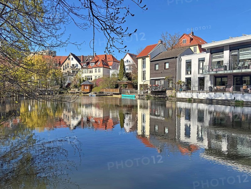 Row of houses on the riverbank with impressive reflection in water and clear blue sky, Braunschweig, Lower Saxony, Braunschweig, Germany