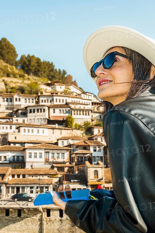 Female traveler viewing historic Berat hillside architecture riverside promenade UNESCO World Heritage city Albania cultural tourism destination