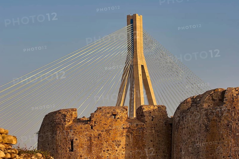 Detailed view of a modern bridge behind old castle walls in the warm light of the evening sun, Rio-Antirrio cable bridge, Rio fortress, Patras, Peloponnese, Greece