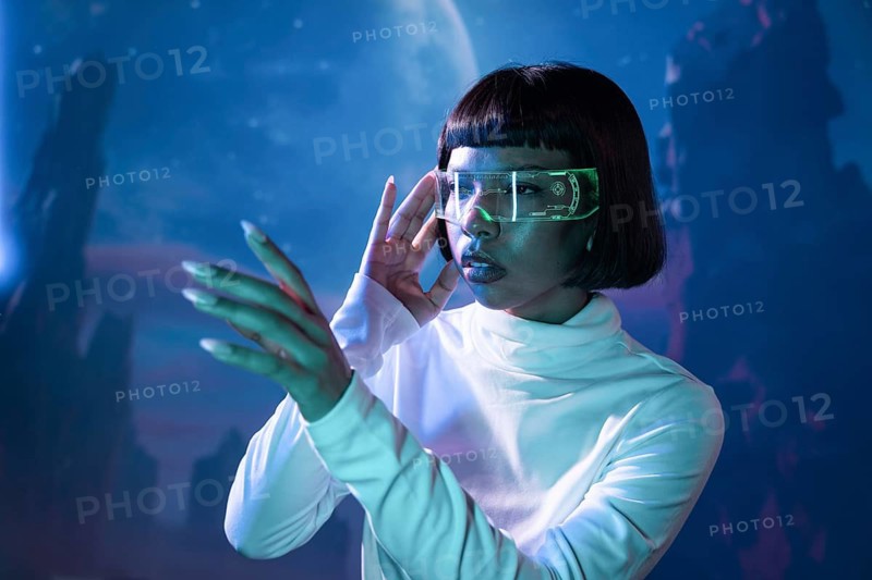 Latin woman in futuristic attire explores virtual reality using advanced VR glasses, immersed in a digital landscape. The concept highlights modern technology and innovation