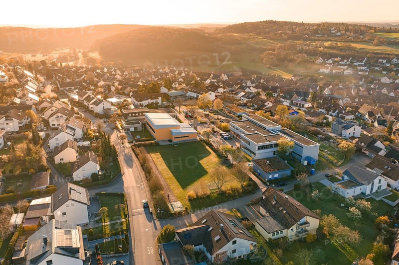 Suburban area with residential buildings and roads in hilly surroundings, sunset in the background, Schlehengäuschule, Gechingen, Hecken and Gäu region, Calw district, Germany