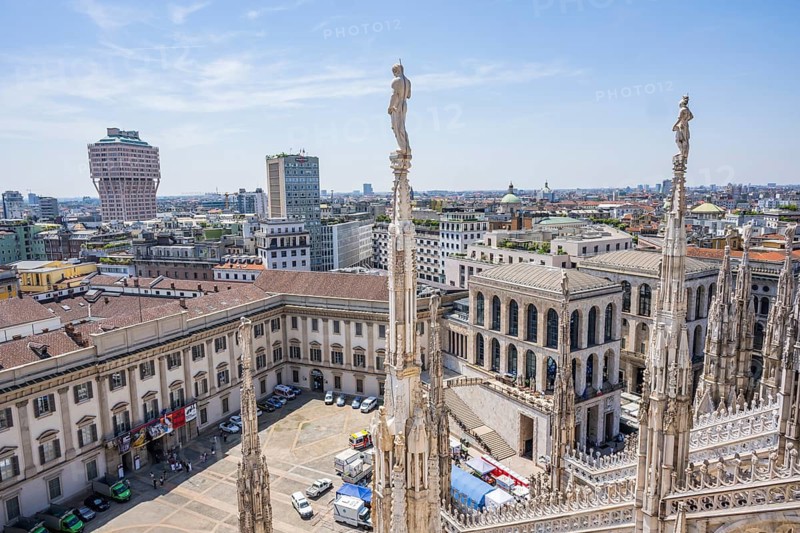Sculptures of saints gaze down on the city from Milan Cathedral on a sunny day, Milan, Italy