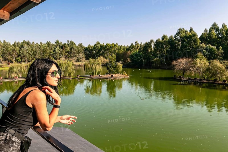 Caucasian woman on viewpoint platform looks right with green nature and lake in the background. Blank space image. Dendrological park.Batumi.Georgia