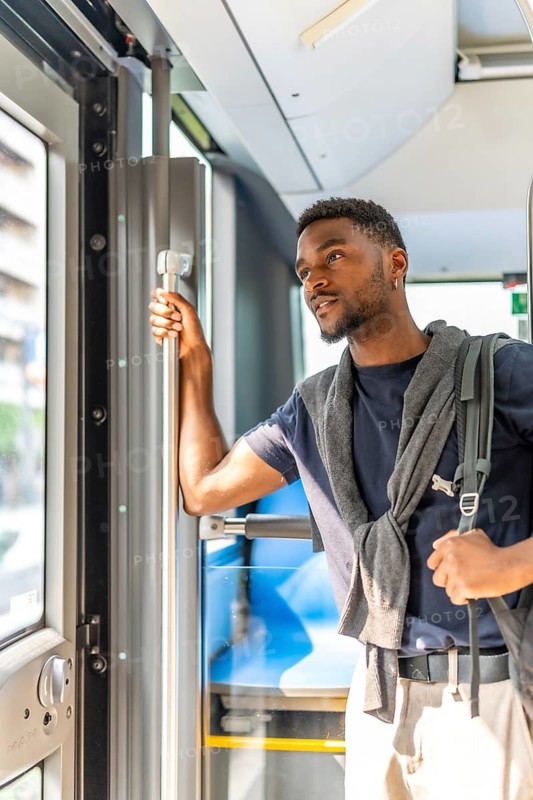 Vertical photo of a casual african businessman on the public bus on the way to work in the morning