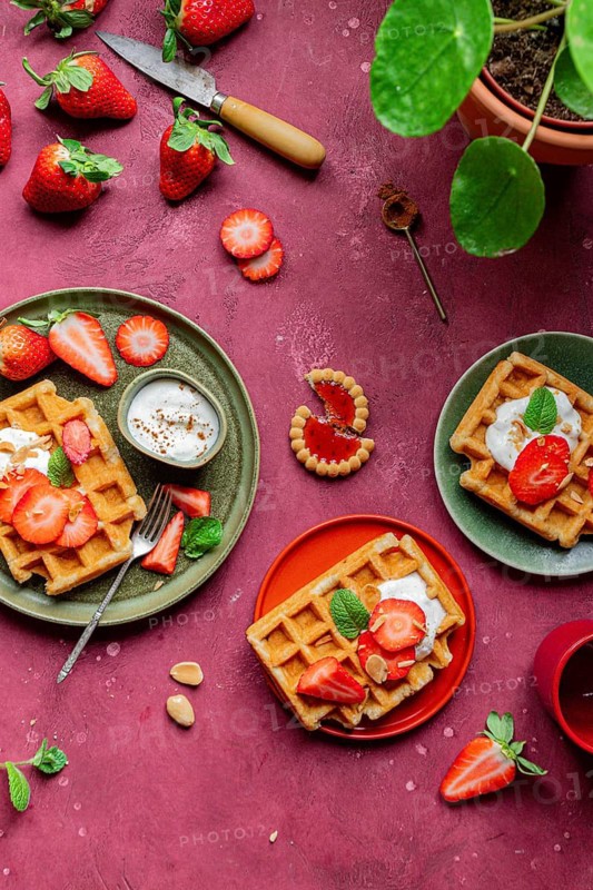 A rustic setting with homemade waffles topped with fresh strawberries and yogurt. Garnished with mint, this romantic dessert is perfect for those with a sweet tooth