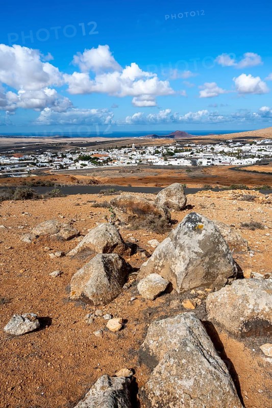 View of town, white houses of Teguise with church tower in dry volcanic landscape, view from Guanapay volcanic crater, Lanzarote, Canary Islands, Spain