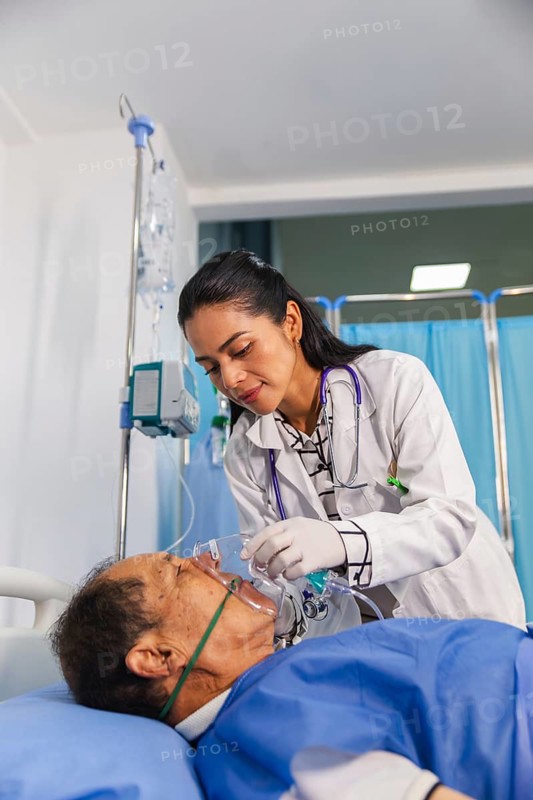 A compassionate doctor attentively assists a patient in a hospital room, ensuring proper care with medical equipment and oxygen support, highlighting dedication in healthcare settings