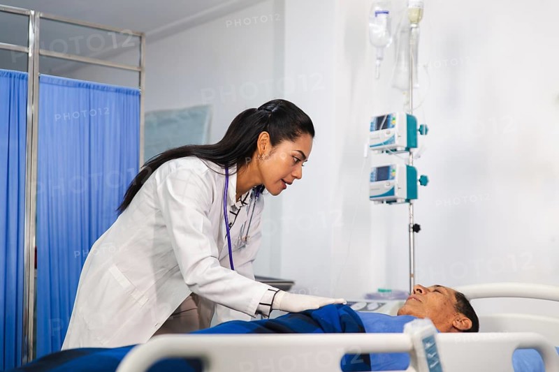 A compassionate female doctor in a white coat attentively cares for an elderly patient in a hospital bed, ensuring comfort and monitoring medical equipment in a serene room