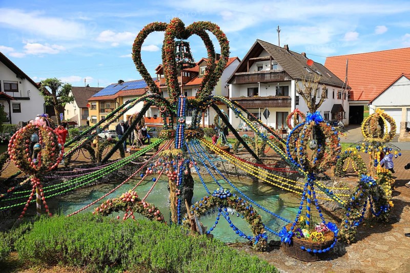 Easter fountain, one of the world's largest Easter fountains, Franconian Switzerland, Bieberbach, Egloffstein market, Forchheim district, Upper Franconia, Bavaria, Germany, colorful Easter fountain in a village square, decorated with many Easter eggs and people in the background