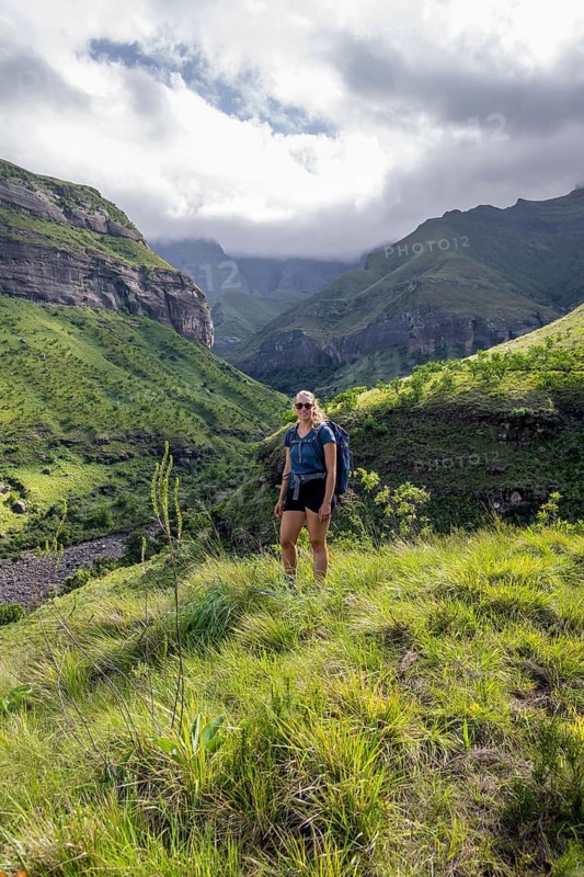Young female hiker between mountains, Drakensberg National Park, KwaZulu Natal, South Africa