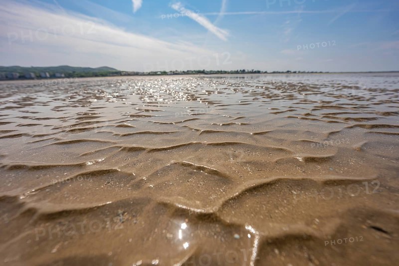 Wide area of wet sand with a wavy pattern under bright sky, low tide, Howth beach, Ireland
