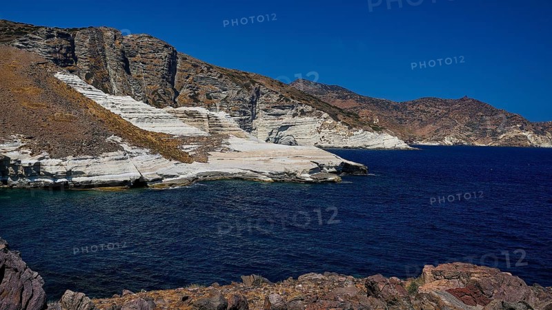 Steep rocks with limestone on the coast with blue sea and dry hills, white volcanic strata, bizarre white rocks in the sea, Little Sarakiniko, Kioni Beach, Kioni, Kimolos Island, Cyclades, Greek Islands, Greece