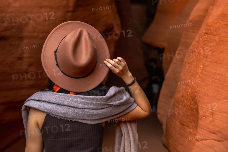 Woman wearing a hat and scarf exploring the narrow, winding sandstone walls of antelope canyon, enjoying the natural beauty and adventure of the iconic american southwest destination