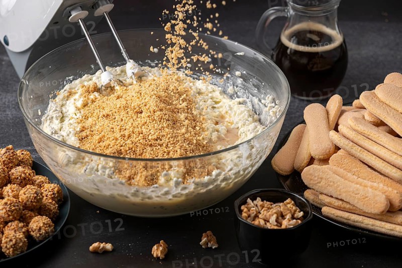 Nuts fall into a bowl of curd cream, with sponge cake and coffee