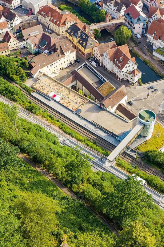 A train station with rails and buildings surrounded by green vegetation in summer, Hermann-Hesse-Bahn, Calw, Germany