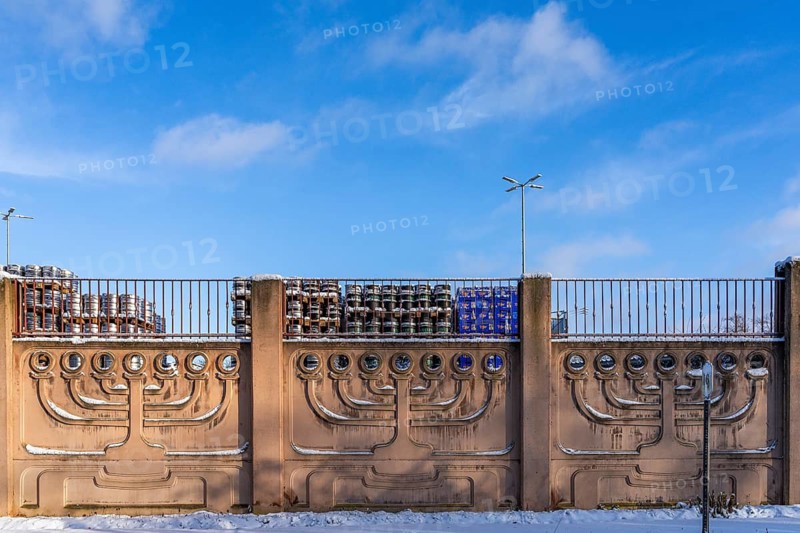 Menorah, seven-armed Judaism chandelier, on a wall in winter, stacks of beer barrels and crates with drinks in the back, Weissensee Jewish Cemetery, Berlin Pankow-Weissensee, Germany