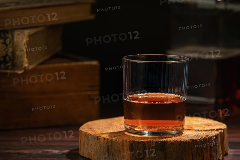 Glass of whiskey on a rustic wooden slice in a cozy atmosphere