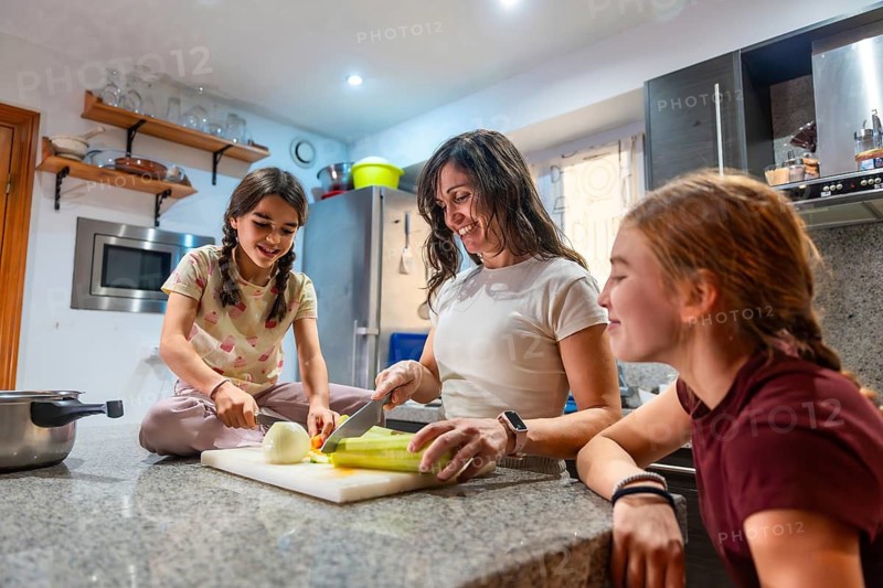 Mother and daughters happily engaging in healthy cooking activities in their kitchen, preparing fresh vegetables and enjoying quality time bonding as a family