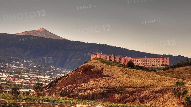Puerto de la Cruz, large building on the slope of a mountain during golden hour, volcano in the background, Teide National Park, Teide National Park, volcano, volcanism, UNESCO World Heritage Site, Tenerife, Canary Islands, Spain