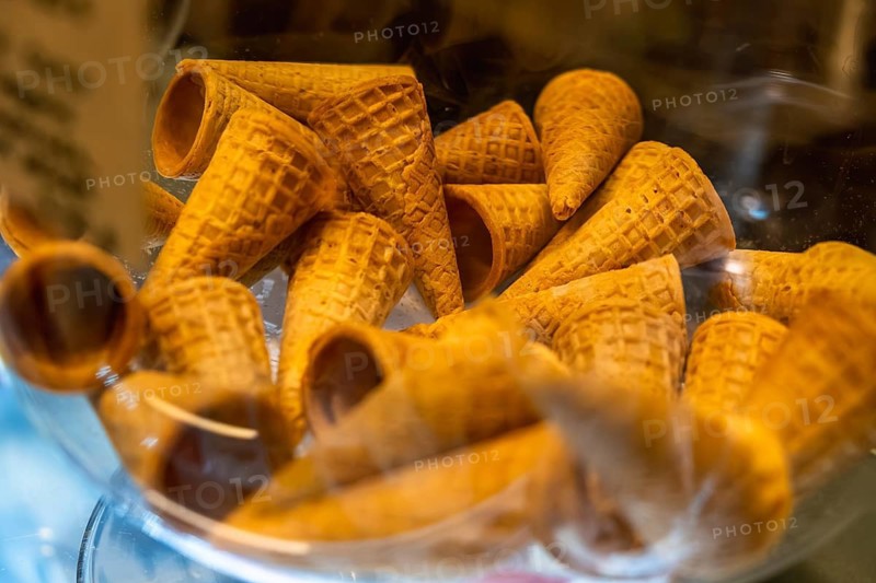 Waffle ice cream cones featuring a textured pattern, stored together in a transparent glass container, offering a delicious snack option and an essential dessert component for summer treats