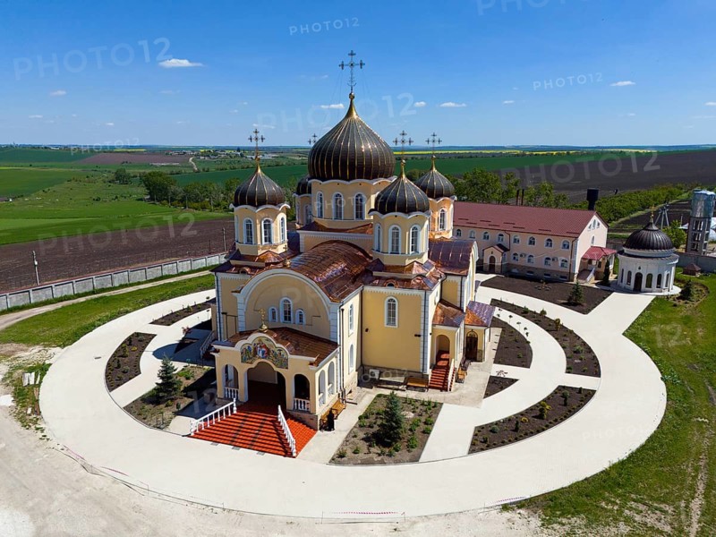 Orthodox church with several domes and crosses surrounded by green landscape under blue sky, aerial view, Nicoreni monastery Sf. Ilie, Nicoreni, Drochia, Bessarabia, Republic of Moldova, Moldova