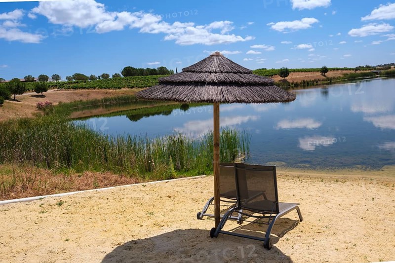 Deckchair under an sunshade with a view of a peaceful lake and natural surroundings, Pedrógão, Beja, Portugal
