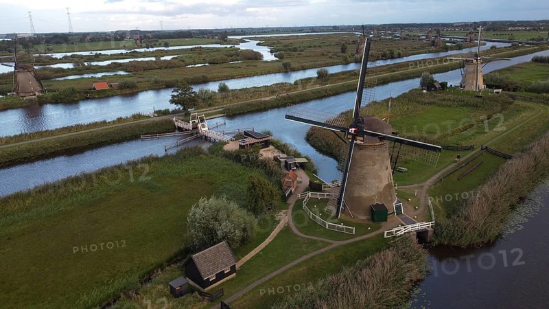 Several windmills along a river in a green landscape with bridges and waterways, windmills along a river in a vast, green landscape under a sunny sky, aerial view, windmills, Kinderdijk, Overwaard-Polder, UNESCO World Heritage, South Holland province, Zuid-Holland, Netherlands
