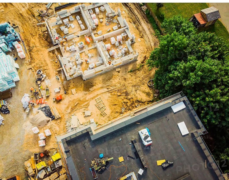 Aerial close up New Constructions real estate Development Site. Urban Construction Site, Aerial View. Rooftops and building construction site with worker laying material.Siauliai. Lithuania