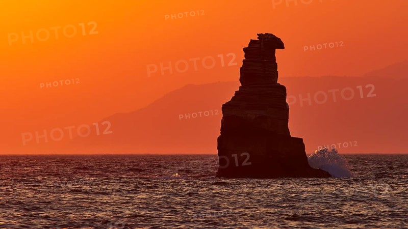 Rock formation in the sea against an intense orange sky during sunset, south of the Amari Basin, Central Crete, Triopetra, rocks in the sea, Crete, Greek Islands, Greece