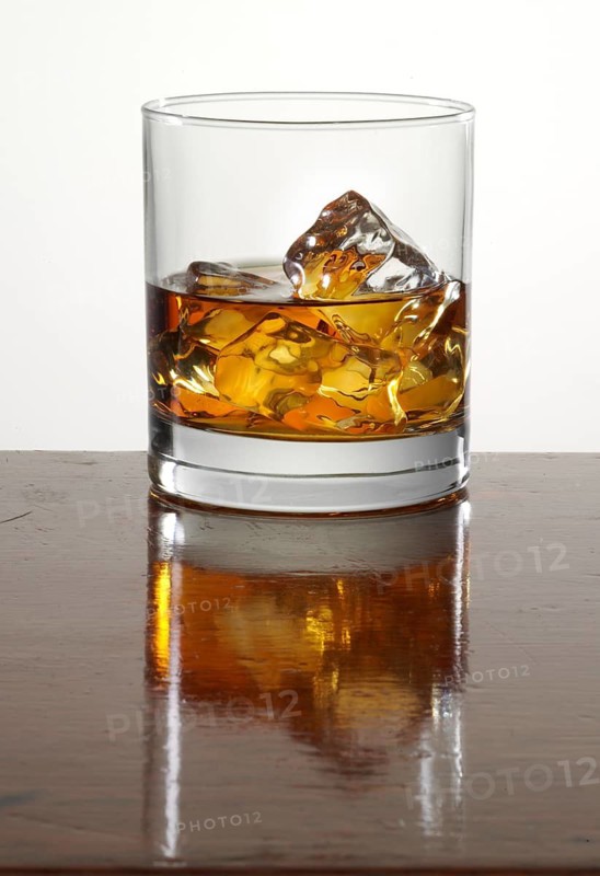 Cocktail in a tumbler on ice standing on bar counter, studio shot