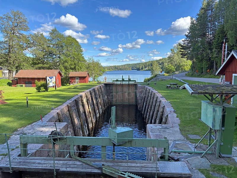 Quiet lock in rural countryside with views of the lake and surrounding wooden houses under blue skies, Högsbyn, Dals-Rostock, Dalsland Canal, Dalsland, Västra Götland Län, Sweden