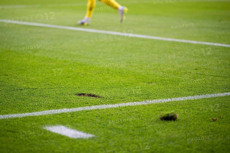 Close up on a damaged green grass turf with a divot on the white line during a soccer match in Wroclaw, Poland