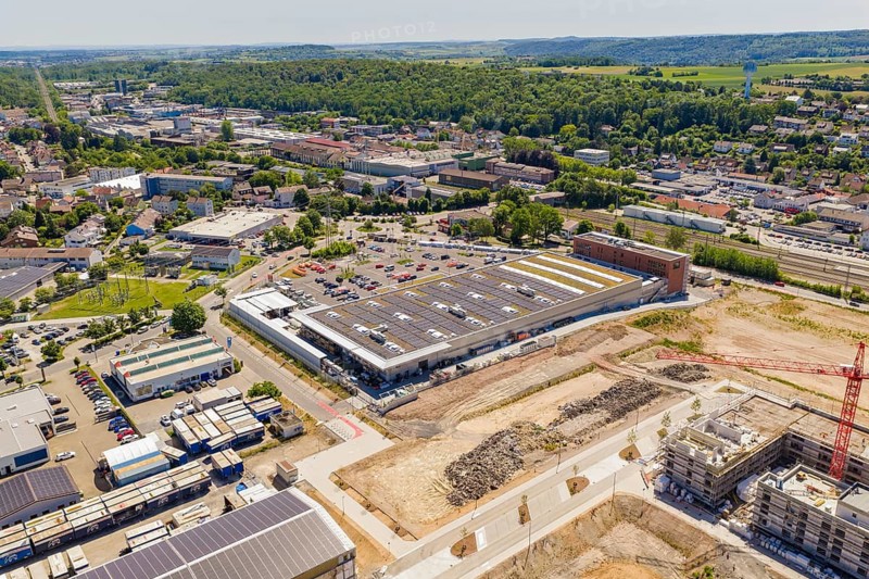 Wide-angle view of an urban landscape with industrial buildings, solar panels and surrounding nature, PV system at OBI Baumarkt, Mühlacker, Enzkreis, Germany