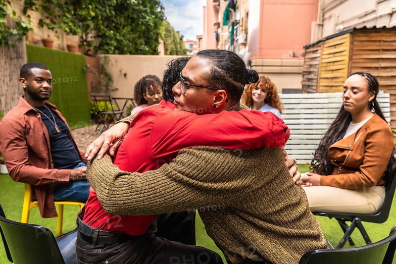 Diverse adults sharing empathetic support and connection during a mental health group therapy session outdoors, fostering healing and understanding in a community setting