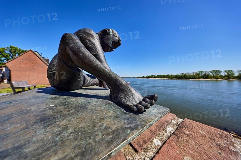 Bronze sculpture Friendship connects, boy, sculptor Jürgen Ebert, brick wall, river Rhine, trees, depth of focus, blue sky, cloudless, Rhine promenade, Rees, Kleve district, North Rhine-Westphalia, Germany