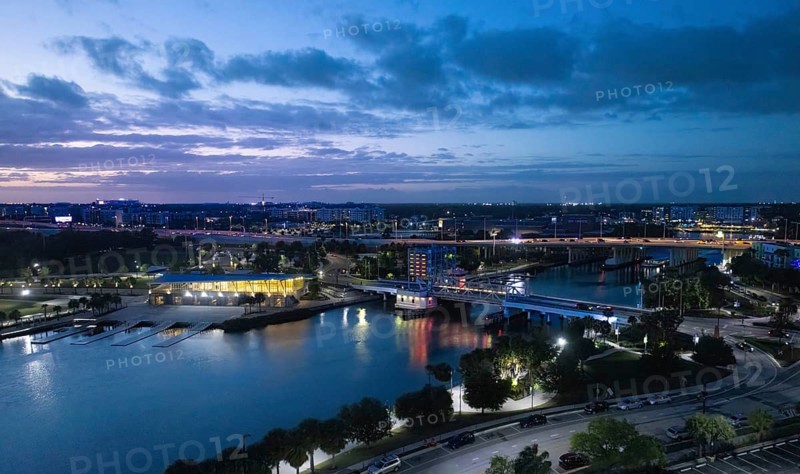 High angle evening view of the Tampa city skyline in Florida with illuminated buildings a drawbridge over the Hillsborough River and waterfront park at twilight